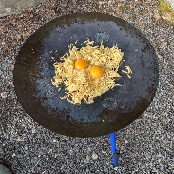 Outdoor cooking stove with noodles and eggs frying